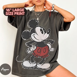Puede incluir: Camiseta gris oscuro con un gran gr&aacute;fico de Mickey Mouse. El dise&ntilde;o incluye un contorno negro y pantalones cortos rojos. El texto "16" LARGE SIZE PRINT" es visible. La camiseta tiene un aspecto vintage y desgastado.