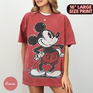 Puede incluir: Camiseta de color rojo carmes&iacute; con un gran gr&aacute;fico de Mickey Mouse. El personaje de dibujos animados est&aacute; representado en negro, blanco y rojo. La camiseta tiene un aspecto desgastado y el texto "16" LARGE SIZE PRINT" es visible.