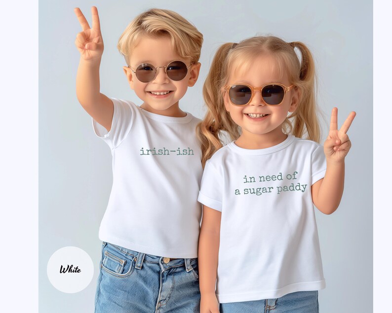 K&ouml;nnte beinhalten: Zwei Kinder mit wei&szlig;en T-Shirts und Sonnenbrillen. Auf einem Shirt steht "irish-ish", auf dem anderen "in need of a sugar paddy". Beide Kinder l&auml;cheln und zeigen das Peace-Zeichen.