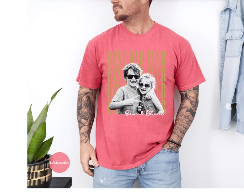 May include: A red t-shirt with the text "BEST DAD EVER" in gold lettering. The shirt features a black and white photo of two children wearing sunglasses. The names "Sam & Olivia" are printed below the photo.
