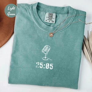 May include: Light green t-shirt with a white outline of a microphone and the text "25:05".