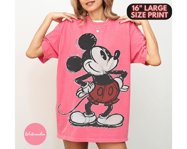 Puede incluir: Una camiseta rosa con un gran gr&aacute;fico de Mickey Mouse. El personaje de dibujos animados es en blanco, negro y rojo. La camiseta tiene el texto "16" LARGE SIZE PRINT" en la parte superior y "Watermelon" en un c&iacute;rculo rosa en la parte inferior.