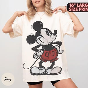 Puede incluir: Camiseta de gran tama&ntilde;o de color marfil con un gr&aacute;fico grande y desgastado de Mickey Mouse. El personaje de dibujos animados est&aacute; representado en negro, rojo y blanco. El texto "16" LARGE SIZE PRINT" es visible en la parte superior derecha.