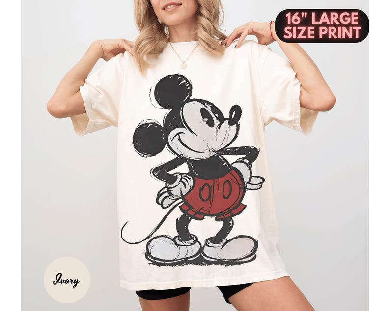 Puede incluir: Camiseta de gran tama&ntilde;o de color marfil con un gr&aacute;fico grande y desgastado de Mickey Mouse. El personaje de dibujos animados est&aacute; representado en negro, rojo y blanco. El texto "16" LARGE SIZE PRINT" es visible en la parte superior derecha.