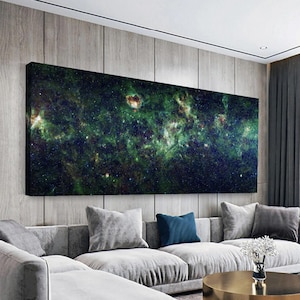 Könnte beinhalten: Ein großer rechteckiger Leinwanddruck, der ein detailliertes Bild einer Galaxie zeigt. Das Kunstwerk weist Farbtöne von Grün, Blau und Braun auf, mit zahlreichen Sternen und Himmelskörpern. Der Druck ist an einer Wand über einem grauen Sofa angebracht.
