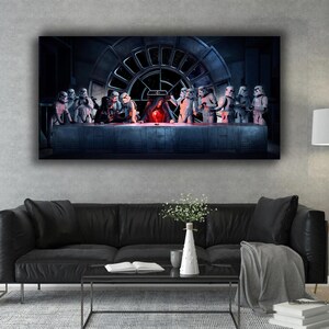 May include: A framed canvas print depicting a parody of The Last Supper, featuring Star Wars characters. Stormtroopers and Darth Vader are seated at a table with a Millennium Falcon window in the background. The artwork is displayed above a black sofa.
