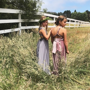 Friends staring off in pasture- One in Grey Satin Twist Shoulder with Leaf hair wreath. Other in twisted one shoulder Mauve Velvet full length dress.