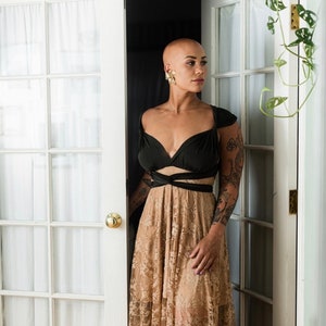 Vintage Urban Garden Bald woman in french doors doorway with plant.
Forest green straps wrapped sweetheart style, Beige lace skirt with mini short gold slip.