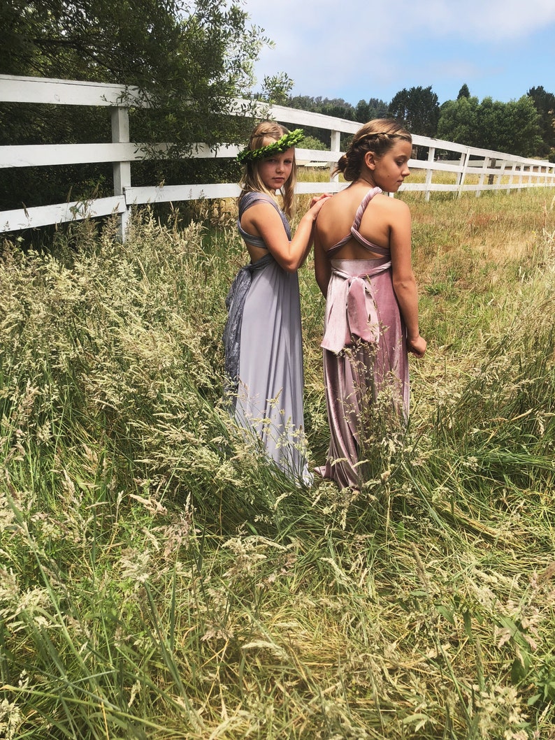 Friends staring off in pasture- One in Grey Satin Twist Shoulder with Leaf hair wreath. Other in twisted one shoulder Mauve Velvet full length dress.