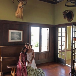 Mother daughter sitting at piano with Antler Head above in Coralie Beatrix  Infinity Dresses. Girl in crushed peony velvet, Woman in Ivory satin with Green Sequin bottom.