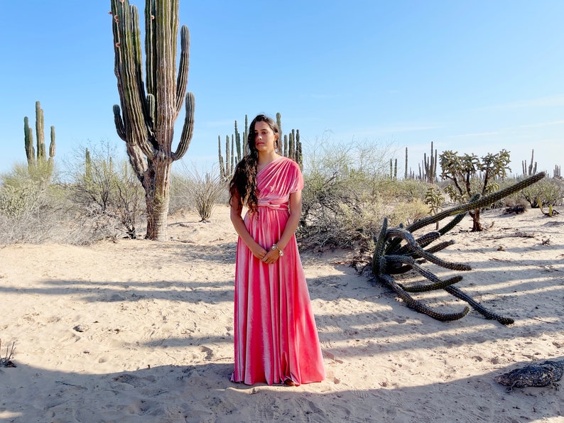 Sunrise Coral Velvet Infinity Wrap Dress worn on one shoulder standing in the desert surrounded by cactus.