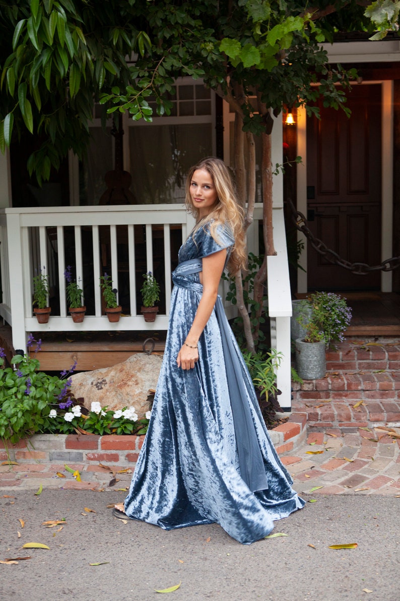 A woman wearing a blue velvet maxi dress with a flowing skirt.