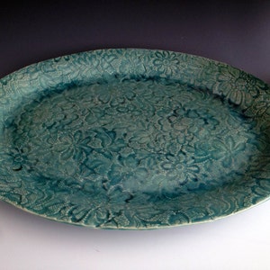 May include: A teal oval ceramic serving platter with a lace-like design.