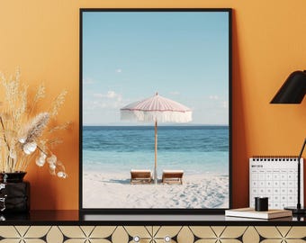 Könnte beinhalten: Gerahmter Strandbilddruck mit einem rosa-weiß gestreiften Sonnenschirm, zwei Holzliegen und einem ruhigen Ozean unter blauem Himmel. Der Druck befindet sich in einem schwarzen Rahmen.