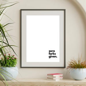 May include: A framed print with a white background and black text that reads "zero forks given."