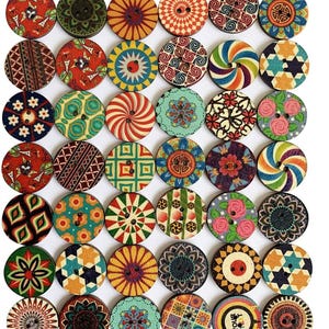 Könnte beinhalten: Eine Sammlung von zweiundvierzig runden Holzknöpfen, die in einem Raster angeordnet sind. Jeder Knopf weist ein einzigartiges, farbenfrohes Druckmuster auf, darunter florale, geometrische, Mandala- und Streifendesigns. Jeder Knopf hat zwei Löcher.