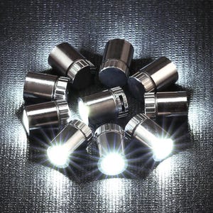 May include: A collection of ten small, cylindrical, metallic silver LED lights arranged in a circular pattern. Several of the lights are illuminated, emitting a bright white glow with visible light rays, while others remain unlit.