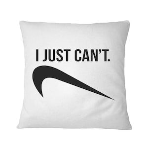 May include: White square pillow with the text "I JUST CAN'T." in black, above a black swoosh design. The pillow is a solid white color.