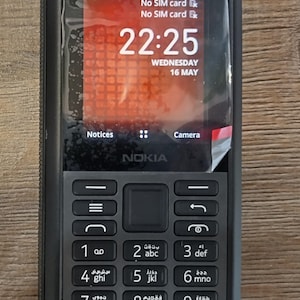 Op de afbeelding: Een zwarte Nokia mobiele telefoon met een robuust frame en een beschermende schermfolie. Het display toont de tijd 22:25, de datum woensdag 16 mei en de tekst No SIM card. Het apparaat is voorzien van een fysiek alfanumeriek toetsenbord.