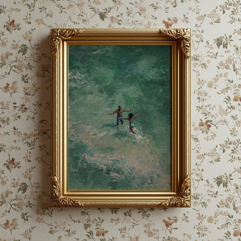 May include: A framed art print depicts two people in the ocean with their arms outstretched. The artwork is in a gold ornate frame and hangs on a floral wallpaper background. The water is a mix of green and white.
