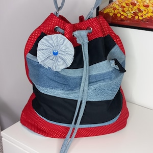Handgemachte Umhängetasche aus wiederverwendeten Jeans mit Ösen und Zugband, rot abgesetzt,verstellbarem Tragegurt aus Jeansstoff, geräumig
