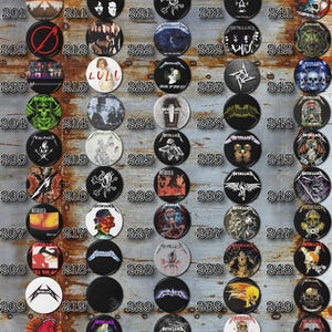 May include: A collection of 50 round metal pinback buttons featuring various Metallica album covers and logos. The buttons are arranged in a grid of 10 rows and 5 columns. The buttons are all different colors and designs, and they are all in good condition.