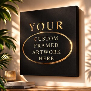 Peut inclure: Une toile murale carrée noire avec le texte doré YOUR CUSTOM FRAMED ARTWORK HERE, entouré d'une bordure ovale dorée. Le design est présenté sur un mur avec un éclairage doux, créant une présentation propre et professionnelle pour cet objet.