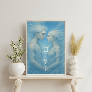 Op de afbeelding: Een ingelijste kunstdruk met een hemelse illustratie van twee figuren met golvend haar, tegen een blauwe achtergrond. Het sterrenbeeld Tweelingen en het woord "GEMINI" worden verticaal weergegeven. Het kunstwerk wordt tentoongesteld op een lichtgekleurde houten plank.