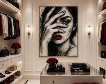 May include: A large framed charcoal-style portrait painting of a person with a hand covering their eyes, featuring vibrant red lips. The artwork is displayed in a walk-in closet with white cabinetry, hanging clothing, handbags, and a central island.