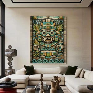 Op de afbeelding: Een ingelijst kunstwerk met een gestileerde, kleurrijke figuur geïnspireerd op de Azteken. Het kunstwerk toont een gedetailleerd ontwerp met geometrische patronen, maïs en waterdruppelmotieven. Het kleurenpalet omvat tinten blauw, groen, geel en bruin. Het kunstwerk wordt boven een witte hoekbank getoond.