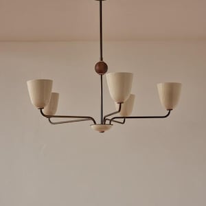 May include: A mid-century chandelier featuring five off-white cone-shaped shades. The central rod and arms are dark brown, with a wooden sphere detail. The light fixture is suspended from the ceiling, a classic design.