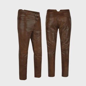 May include: Brown leather trousers with a high waist and a fitted cut. The trousers have a double buckle fastening and a classic five-pocket design. The leather has a distressed appearance, giving the trousers a vintage feel.