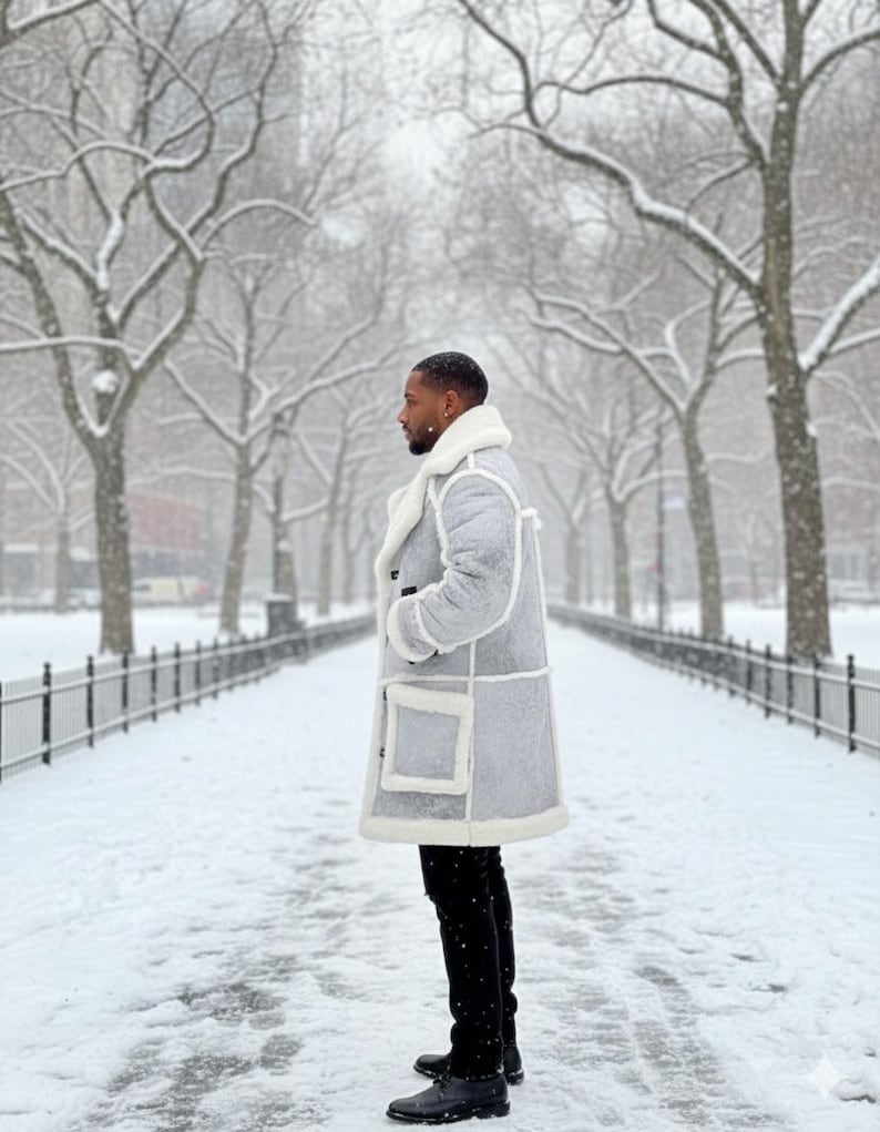 May include: A light gray patchwork coat with a white shearling collar and trim. The coat has large square pockets and is worn with black pants and black boots. The background is a snowy park with bare trees.