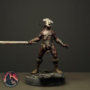 Op de afbeelding: Een gedetailleerd beeldje van een gespierde humanoïde krijger met een donkere huid, die een witte helm en een lendendoek draagt. Het figuur houdt een lang zwaard in één hand, heeft een witte handafdruk op de borst en staat op een rotsachtige basis.