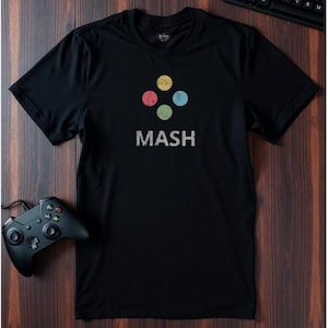Könnte beinhalten: Schwarzes T-Shirt mit einem Retro-Logo mit vier bunten Kreisen und dem Wort "MASH" in weißer Schrift.