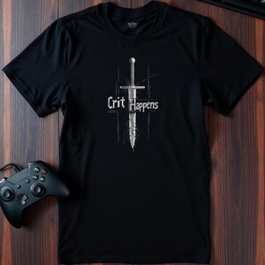 May include: Black t-shirt with a white graphic of a sword and the text "Crit Happens".