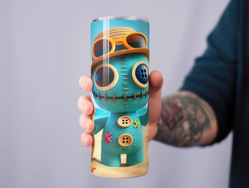 May include: A tall, cylindrical tumbler featuring a cartoon character design. The character is a teal-colored doll with button eyes and a stitched appearance, wearing a straw hat and sunglasses. The tumbler is held by a person.