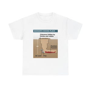 May include: A white t-shirt featuring a graphic diagram titled SADDAM'S HIDING PLACE. The illustration shows a cross-section of an underground bunker, labeled with an entrance hidden by bricks and rubble, a 6ft depth, an air vent, a fan, and a figure.