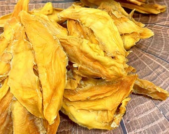 May include: A pile of dried mango slices, showcasing a vibrant yellow-orange hue. The dehydrated fruit pieces have a wrinkled texture and are arranged on a wooden surface, creating a natural and appetizing display. The image highlights the natural food product.