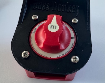 May include: A black battery switch with the text "Bass Donkey" and a red knob with a white indicator. The switch has the text "BLUE SEA SYSTEMS" and "ON" printed on it. The switch is designed for a single circuit.