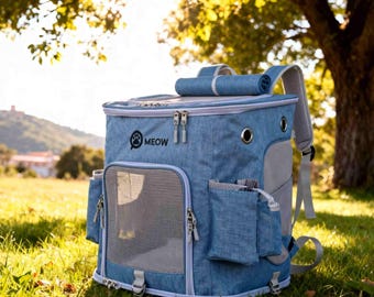 May include: Blue pet carrier backpack with multiple pockets and a mesh window. The backpack has a roll-up top and the word "MEOW" printed on the front, along with a paw print logo. The carrier is designed for pets and is sitting on green grass.