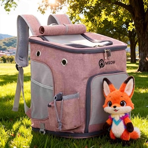 K&ouml;nnte beinhalten: Ein rosafarbener Rucksack f&uuml;r Haustiere mit grauen Akzenten und Mesh-Seitenteilen. Auf dem Rucksack steht das Wort "MEOW" und daneben liegt ein kleines Stofftier in Form eines Fuchses. Der Rucksack steht auf gr&uuml;nem Gras.