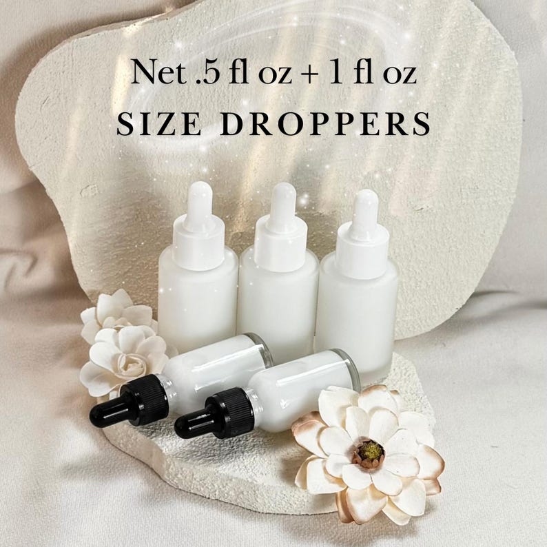 May include: White glass dropper bottles with black droppers are arranged on a textured surface, accompanied by white and cream-colored floral accents. The text "Net .5 fl oz + 1 fl oz SIZE DROPPERS" is displayed at the top.