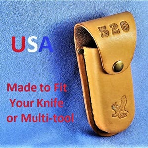May include: Tan leather knife sheath with a snap closure and an eagle logo. The sheath is labeled "520" and "USA".