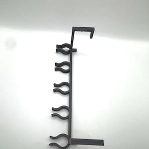 Puede incluir: Organizador de plástico negro con cinco ganchos para colgar artículos. El organizador tiene un gancho en la parte superior para colgar en una pared o estante.