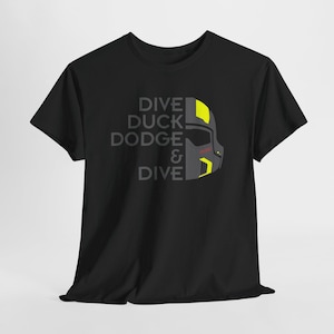 Könnte beinhalten: Schwarzes T-Shirt mit dem Text "DIVE DUCK DODGE & DIVE" in Grau und einer Grafik eines Helms in Grau, Gelb und Rot. Das T-Shirt hat einen Rundhalsausschnitt.