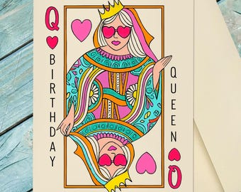 May include: A cream-colored greeting card featuring a playing card design of a queen wearing a yellow crown and pink heart-shaped sunglasses. The queen wears a colorful patterned robe in shades of teal, pink, and orange. Text reads BIRTHDAY QUEEN.