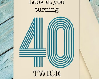 May include: A rectangular greeting card with a cream-colored background featuring the black text Look at you turning and TWICE. Between these phrases is a large number 40 rendered in a teal blue color with a series of parallel vertical lines.