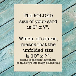 May include: A cream-colored card with black text. The text states the folded size is 5" x 7" and the unfolded size is 10" x 7". The card is on a teal, weathered wood surface.