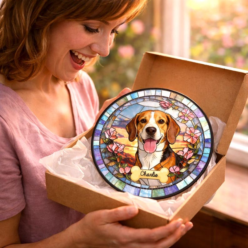 May include: A round, stained-glass style decorative piece featuring a beagle dog with a happy expression, tongue out. The artwork is framed by pink flowers and a blue and purple border. The dog's name, "Charlie", is on a bone-shaped tag.